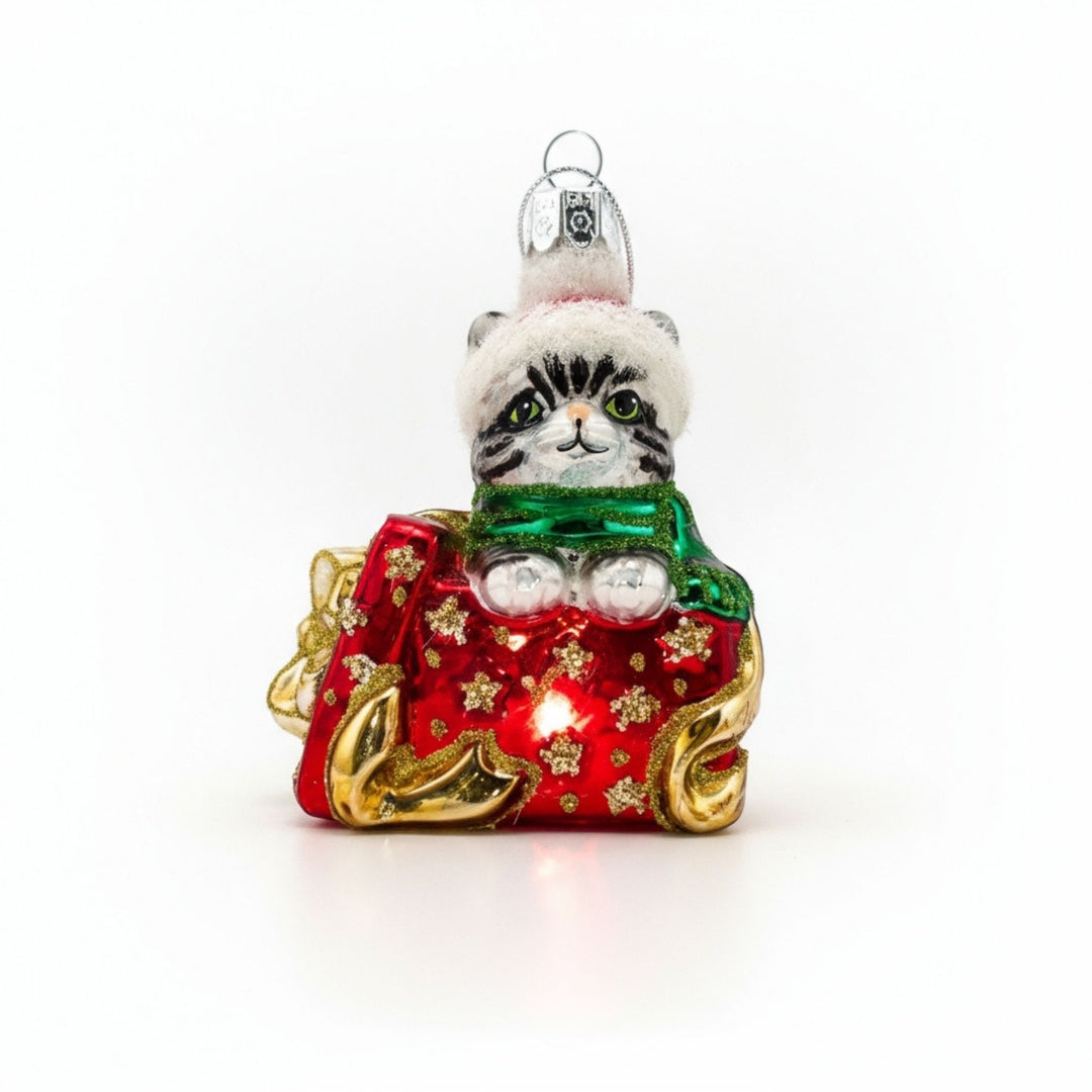 Handcrafted glass ornament of a grey kitten popping out of a Christmas gift box