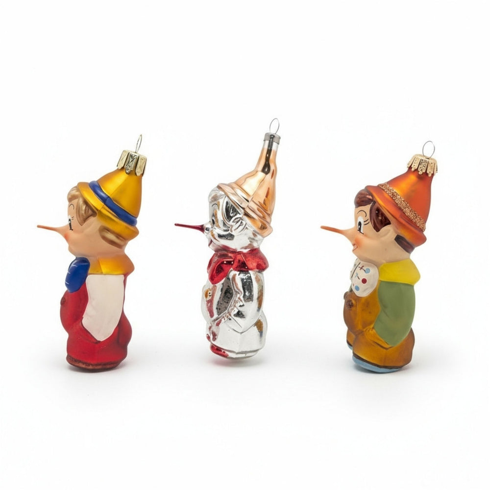 Side view of three Pinocchio glass Christmas ornaments showing color variations by Edmo