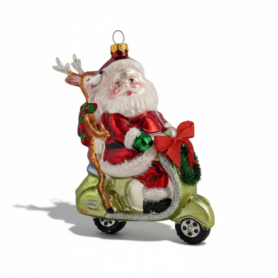 Hand-painted glass Christmas ornament of Santa riding a scooter with a reindeer passenger, decorated with festive glitter details